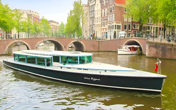 VIP Canal Cruise on Stan Huygens boat in Amsterdam canal with historic bridge.