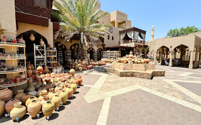 Pottery market in Nizwa, Oman, showcasing traditional clay pots and crafts under palm trees.