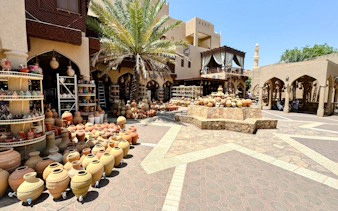 Pottery market in Nizwa, Oman, showcasing traditional clay pots and crafts under palm trees.