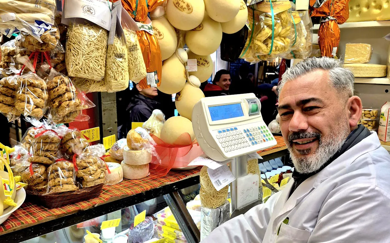 Vendor at Padova market with cheese and pasta display during food tour.