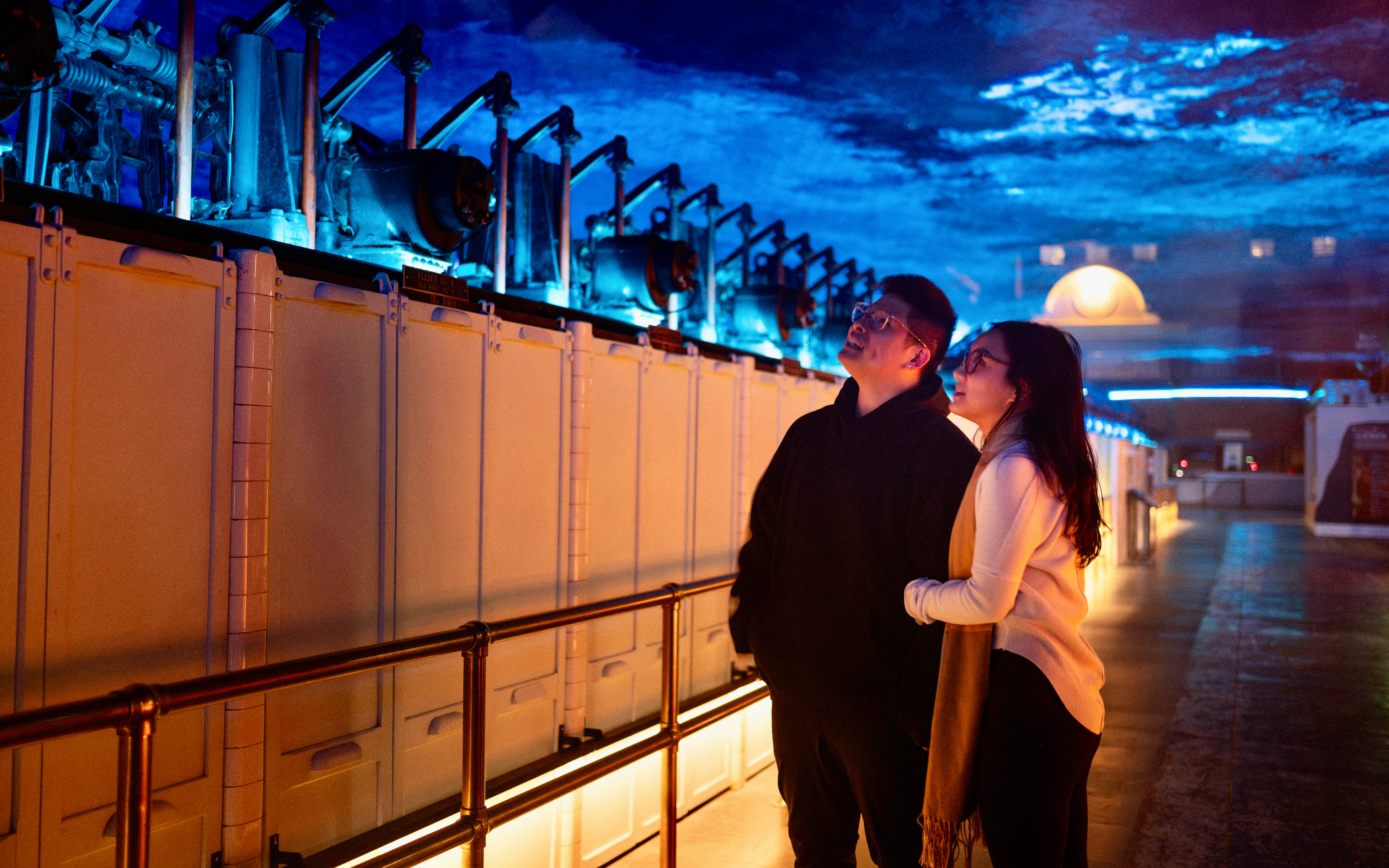 Visitors observing illuminated machinery inside Niagara Parks Power Station at night.