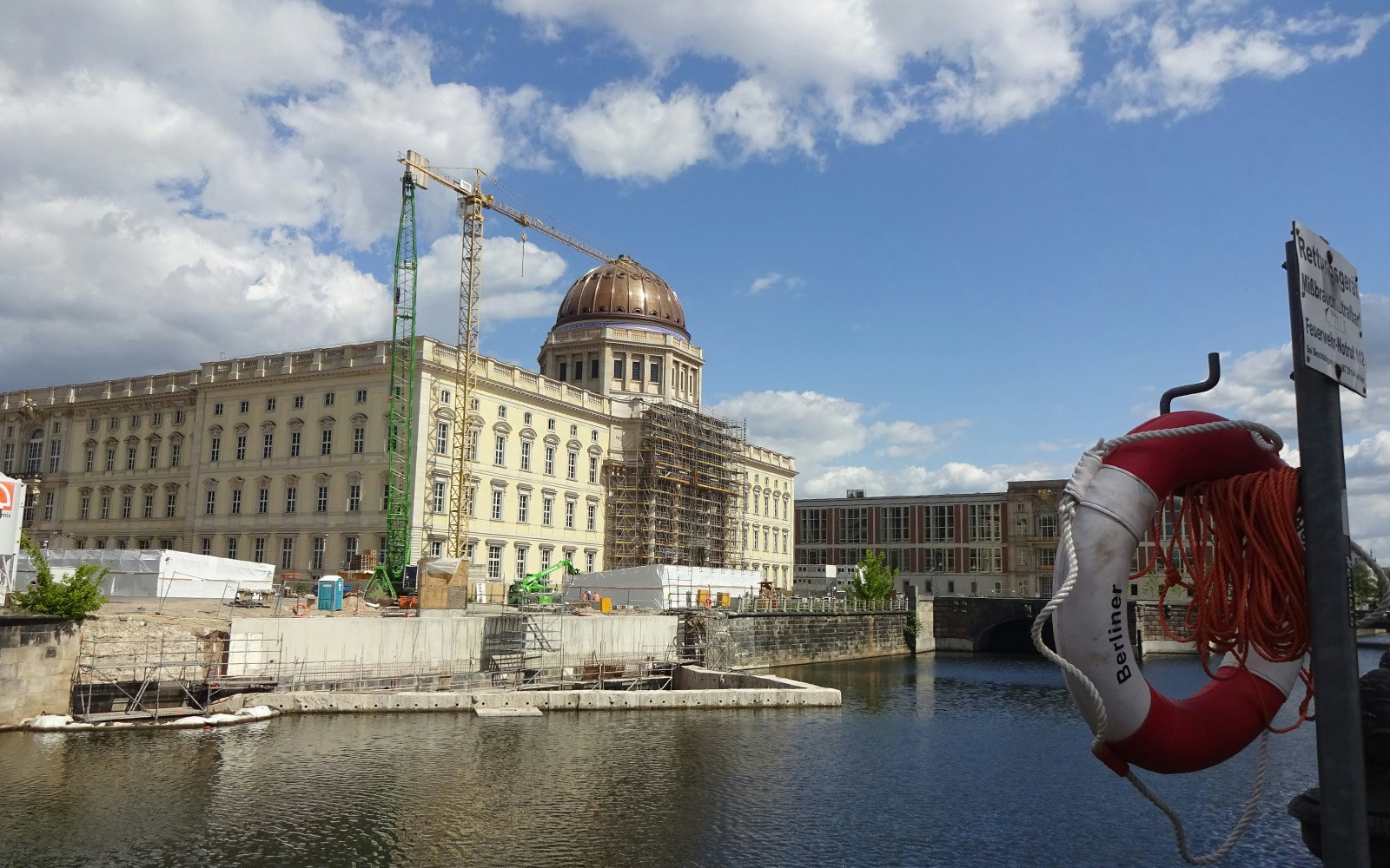 Berlin Palace under construction by the River Spree with a life preserver in the foreground.