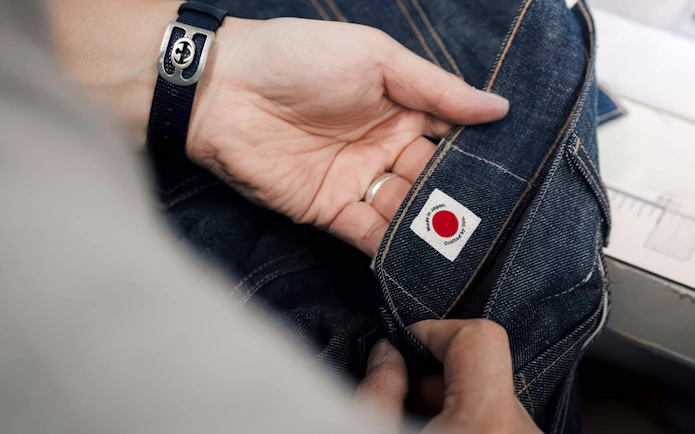 Placing label on jeans during Tokyo Denim Jeans Making Experience in Harajuku.
