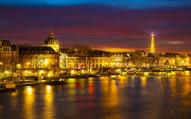 Paris night skyline with Eiffel Tower and Seine River, viewed from Tootbus tour.