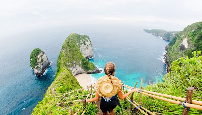 Traveler overlooking Kelingking Beach cliffs on Nusa Penida Island, Bali.