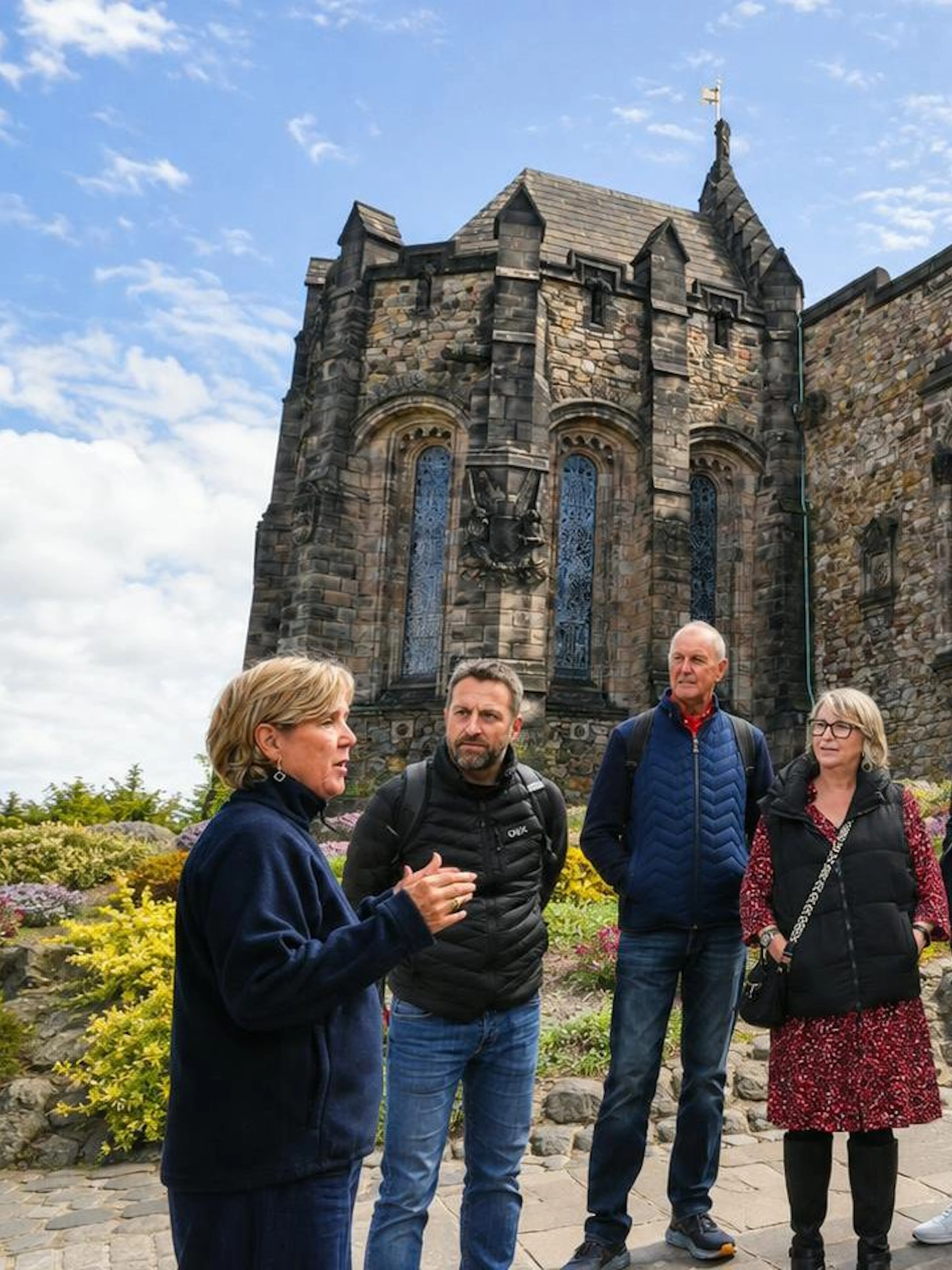 Guided tour group outside historic stone architecture at Edinburgh Castle, Scotland.