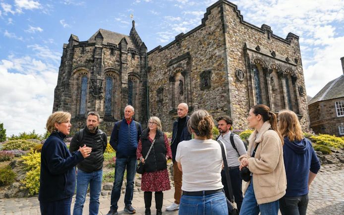 Guided tour group outside historic stone architecture at Edinburgh Castle, Scotland.