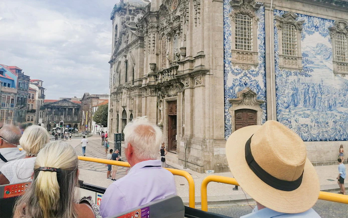 Passengers on a hop-on hop-off bus viewing Igreja do Carmo in Porto.