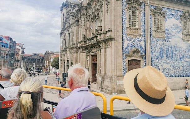 Passengers on a hop-on hop-off bus viewing Igreja do Carmo in Porto.