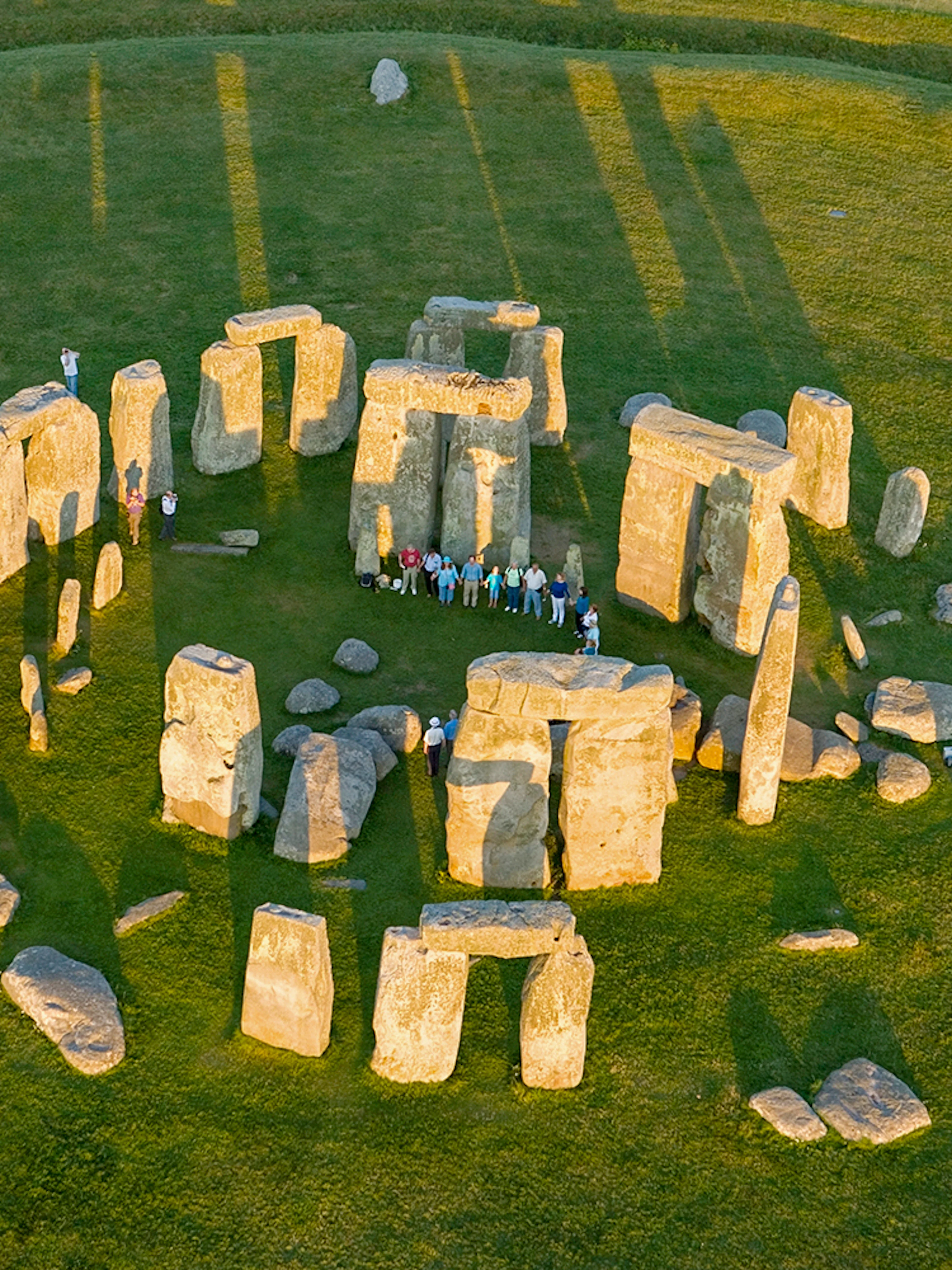 Aerial view of Stonehenge with visitors standing among the ancient stone circle in Wiltshire, England.