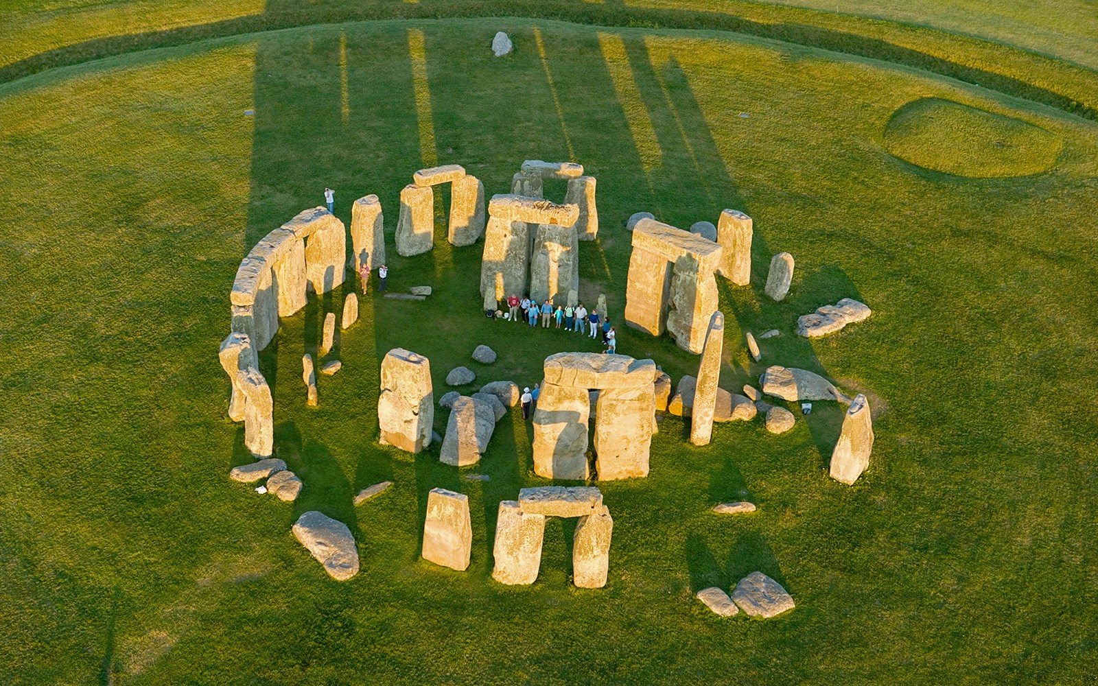 Aerial view of Stonehenge with visitors standing among the ancient stone circle in Wiltshire, England.
