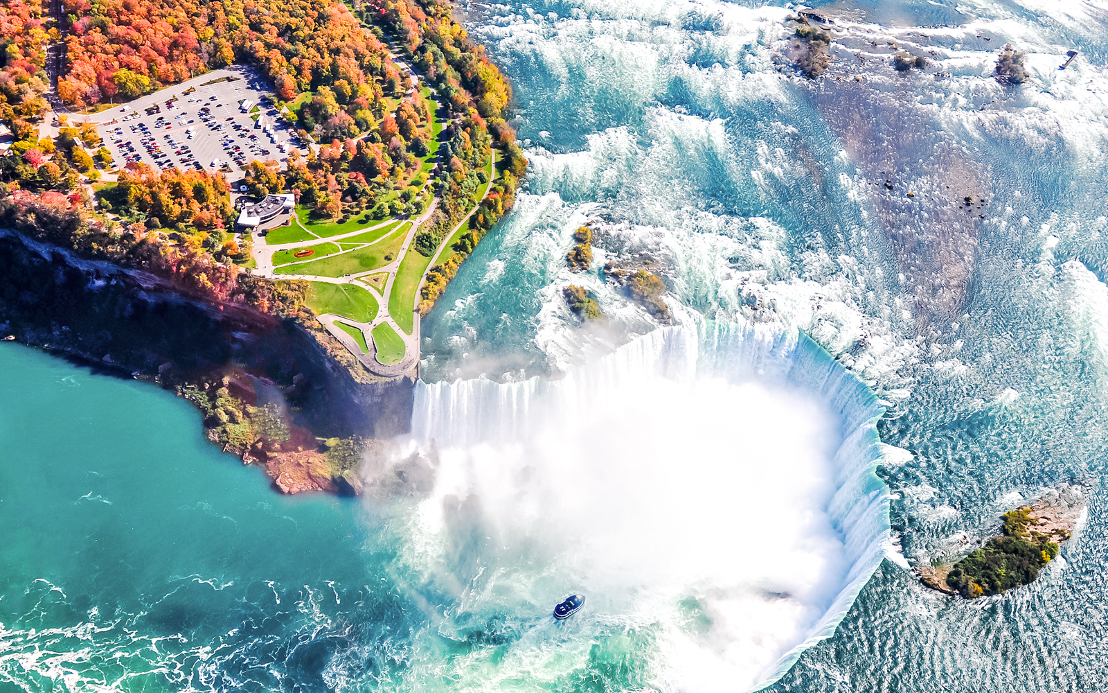 Aerial view of Niagara Falls with cascading water and mist, highlighting the surrounding landscape.