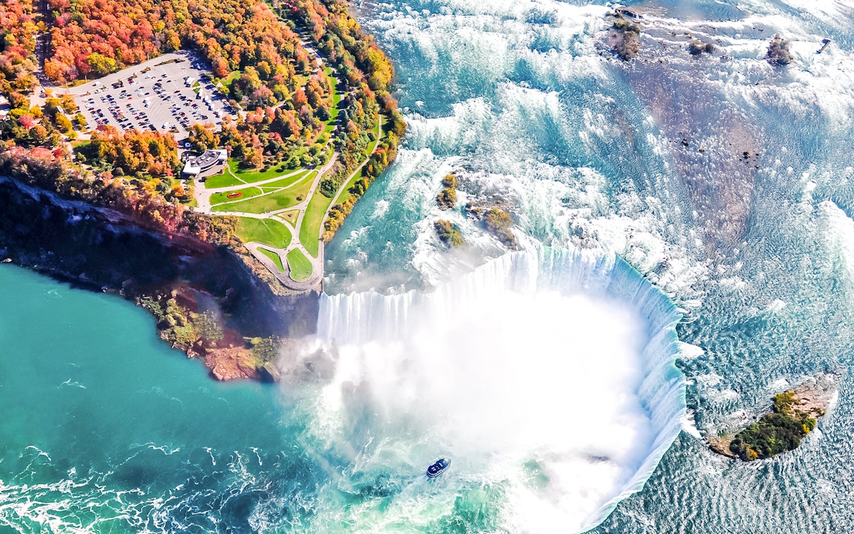 Aerial view of Niagara Falls with cascading water and mist, highlighting the surrounding landscape.