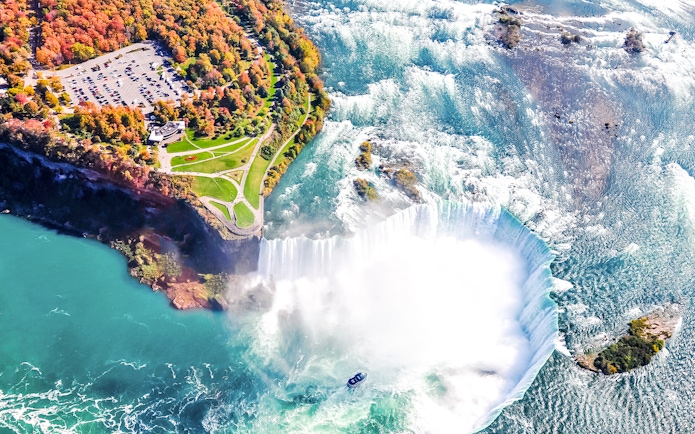 Aerial view of Niagara Falls with cascading water and mist, highlighting the surrounding landscape.