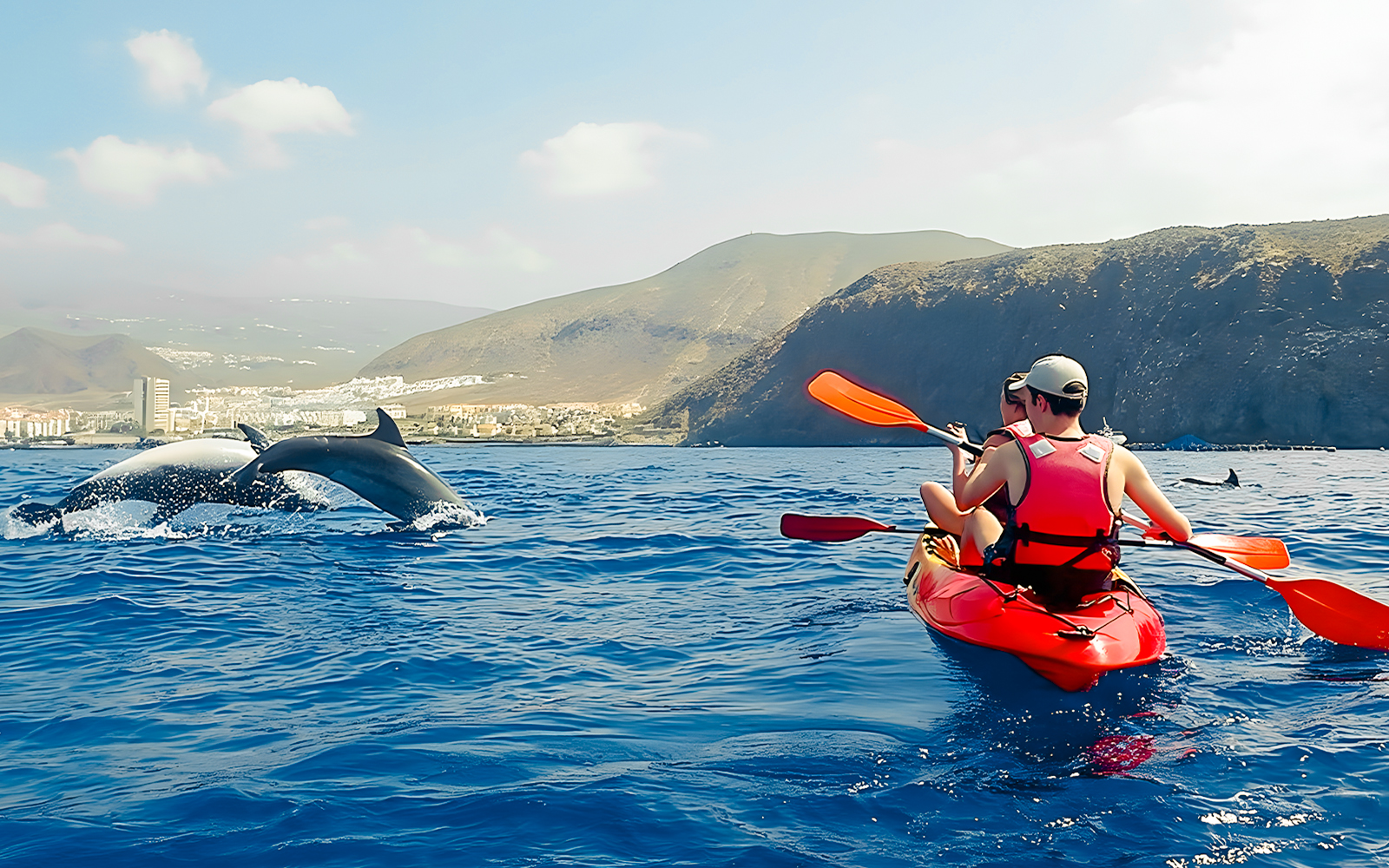 Tourist kayaking near dolphins in Tenerife waters.