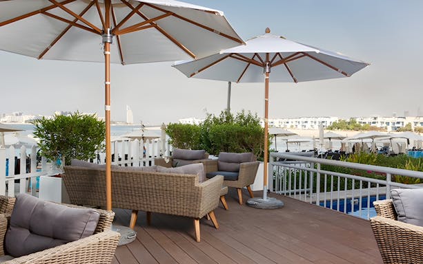 Outdoor seating area at Riva Beach Club with view of Burj Al Arab in Dubai.