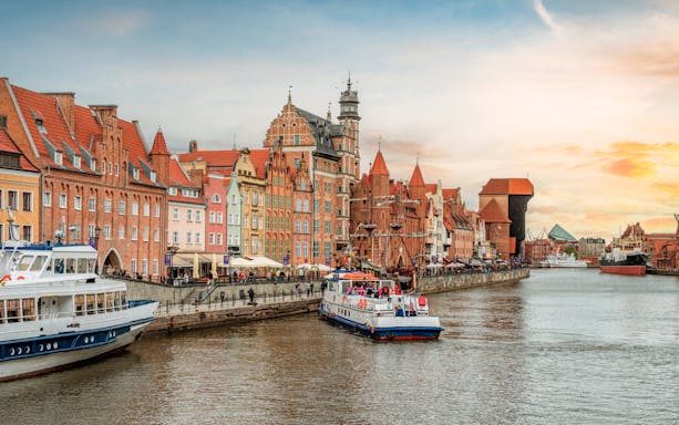 Gdańsk waterfront with historic buildings and boats on the Motława River.