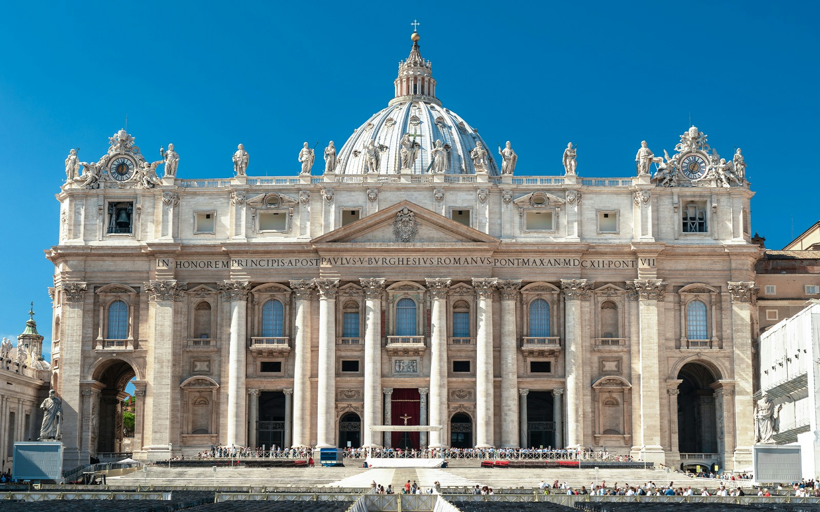 Facade of St. Peter’s Basilica in Vatican City with statues and columns.