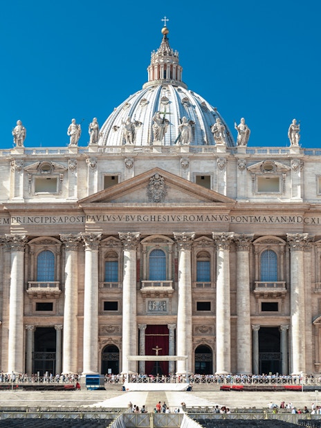 Facade of St. Peter’s Basilica in Vatican City with statues and columns.