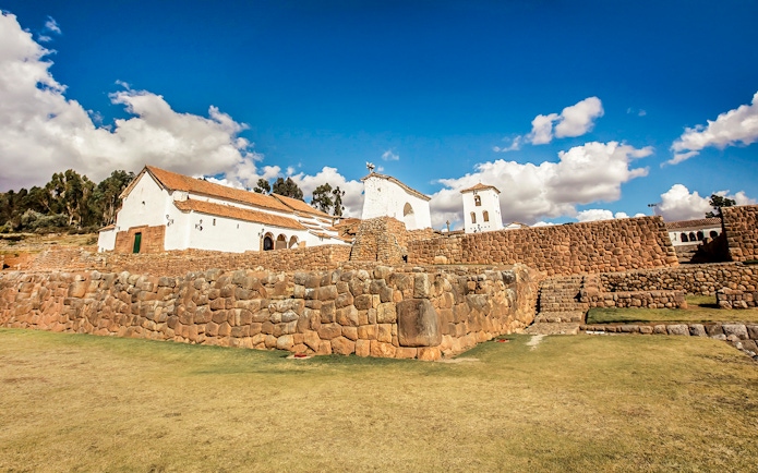 Church of Our Lady of Monserrat with Inca ruins in Chinchero, Peru under a blue sky.
