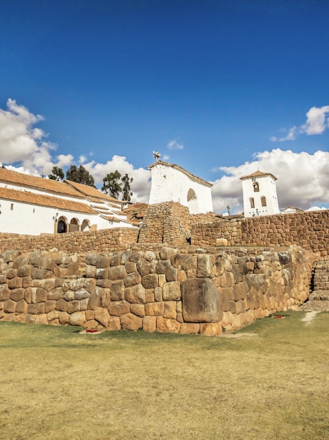 Church of Our Lady of Monserrat with Inca ruins in Chinchero, Peru under a blue sky.