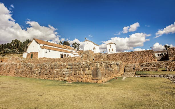 Church of Our Lady of Monserrat with Inca ruins in Chinchero, Peru under a blue sky.