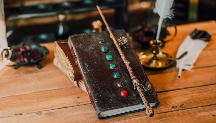 Wand resting on an open book in a magical setting