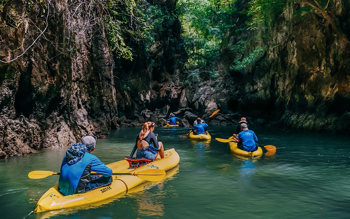 Kayakers exploring a narrow waterway surrounded by lush cliffs on Panak Island.