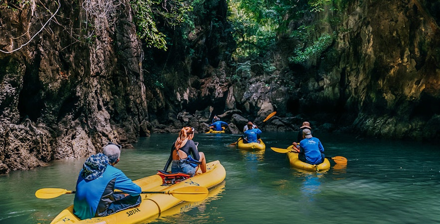 Kayakers exploring a narrow waterway surrounded by lush cliffs on Panak Island.