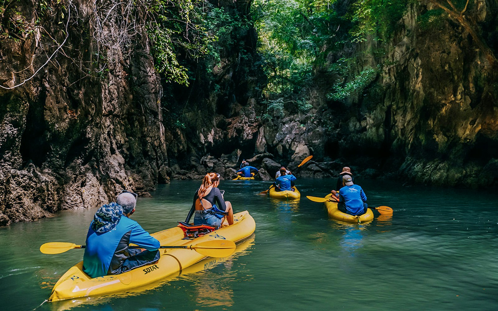 Kayakers exploring a narrow waterway surrounded by lush cliffs on Panak Island.