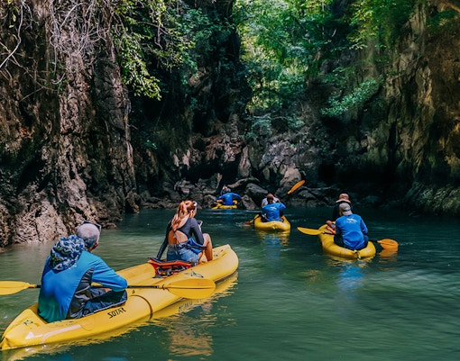 Kayakers exploring a narrow waterway surrounded by lush cliffs on Panak Island.