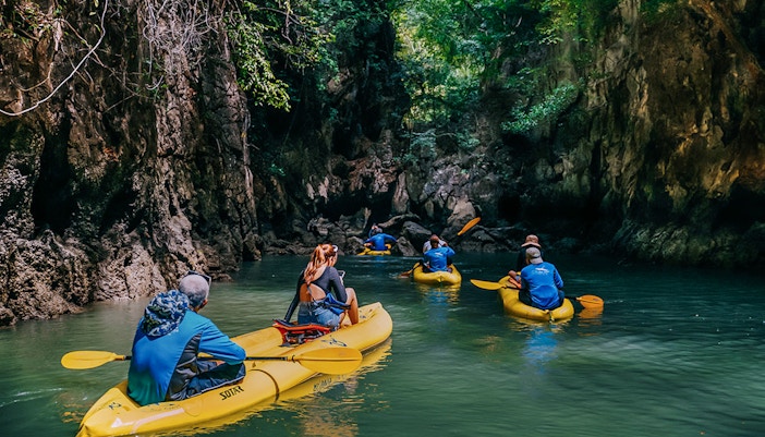 Kayakers exploring a narrow waterway surrounded by lush cliffs on Panak Island.