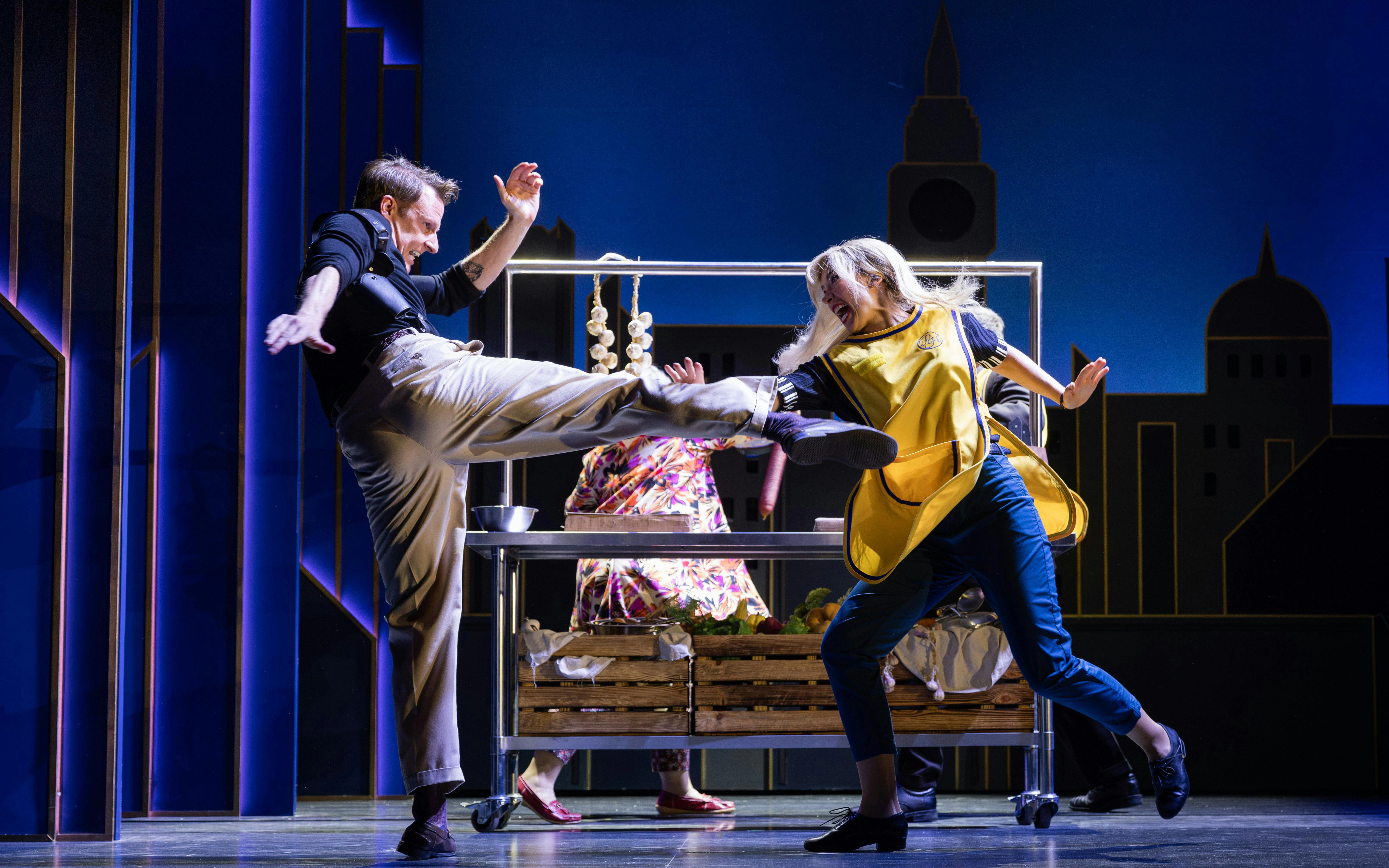 Actors performing a comedic fight scene in "The Comedy About Spies" on stage.