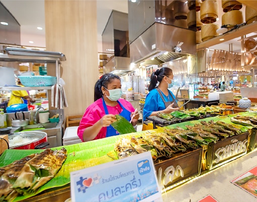 Vendors grilling fish at Ayutthaya Floating Market food stall.