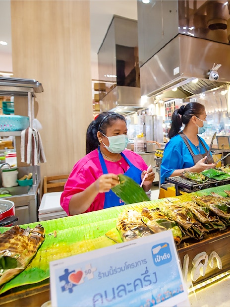 Vendors grilling fish at Ayutthaya Floating Market food stall.