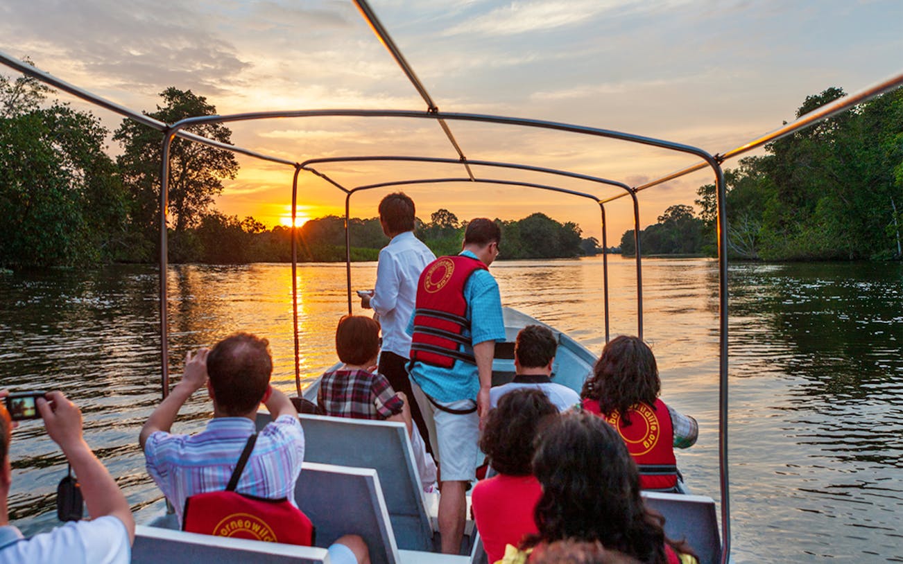 Tourists on a boat during sunset on the Weston Wetland River, Sabah.