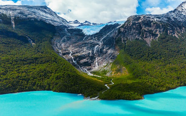 Balmaceda Glacier with turquoise lake in Patagonia, Chile, surrounded by lush forest and mountains.