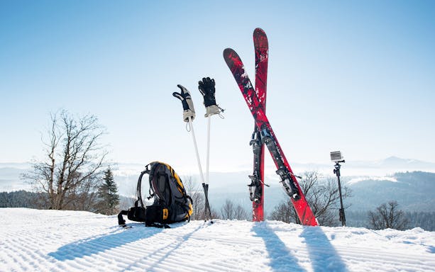 Ski equipment and backpack on snowy mountain with scenic view.