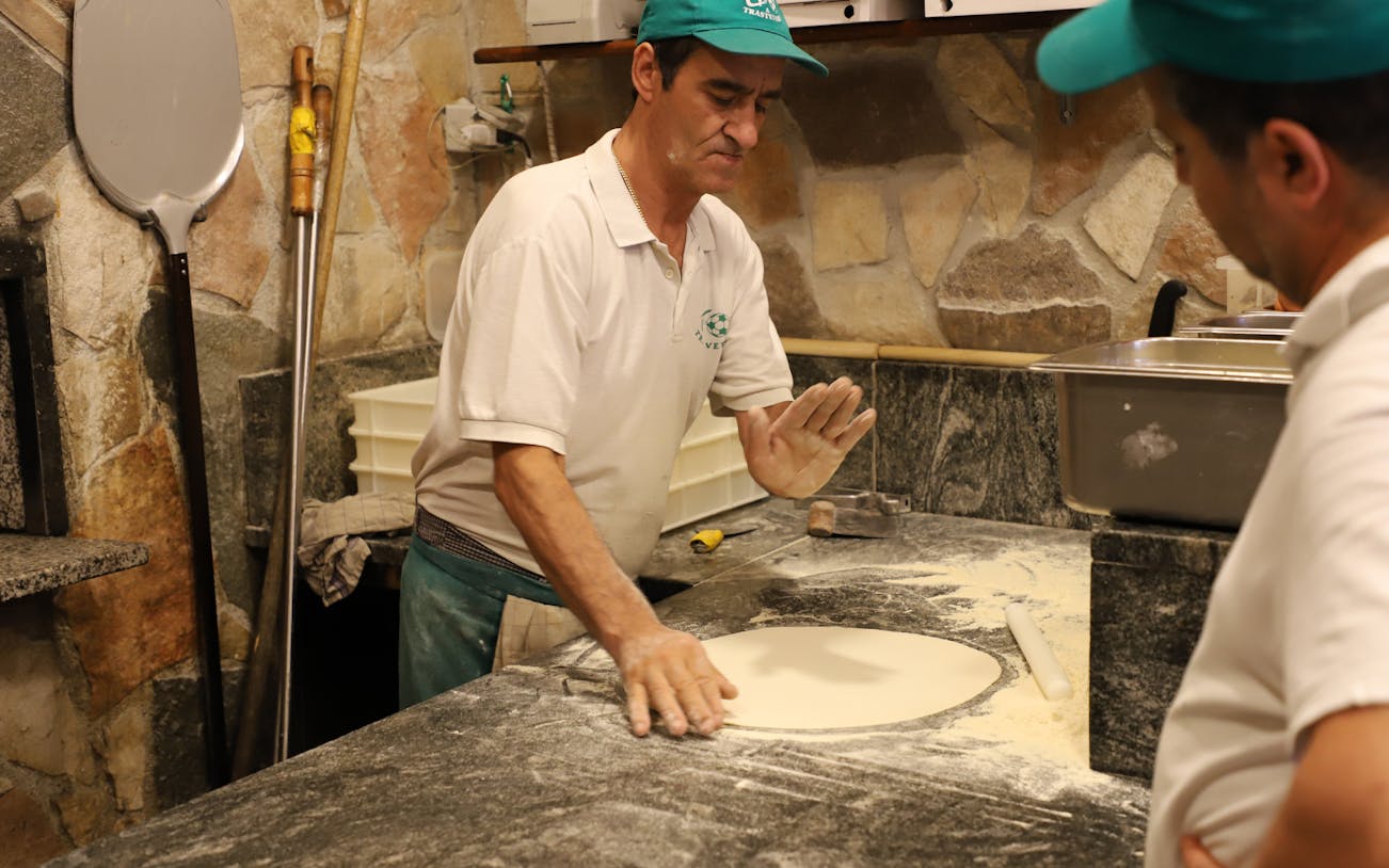 Pizza chef preparing dough in a Trastevere kitchen during a guided food tour.