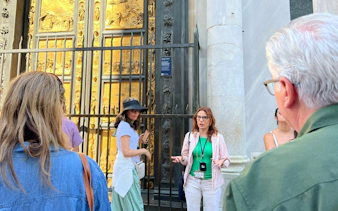 Tour guide explaining the Gates of Paradise at Florence's Baptistery near Uffizi Gallery.
