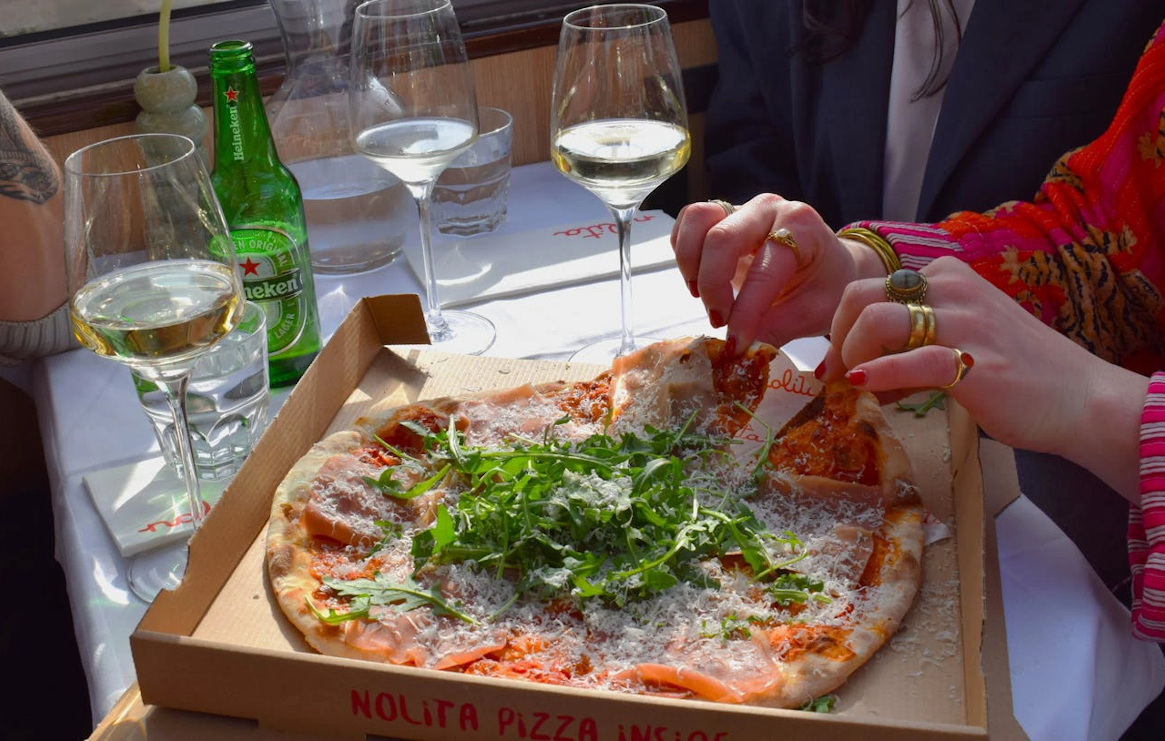 Freshly baked Nolita pizza on Haarlem canal dinner cruise table with wine glasses.