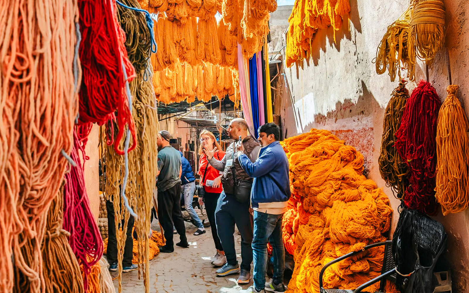 Visitors exploring vibrant yarn displays in Marrakech souks during a private shopping tour.