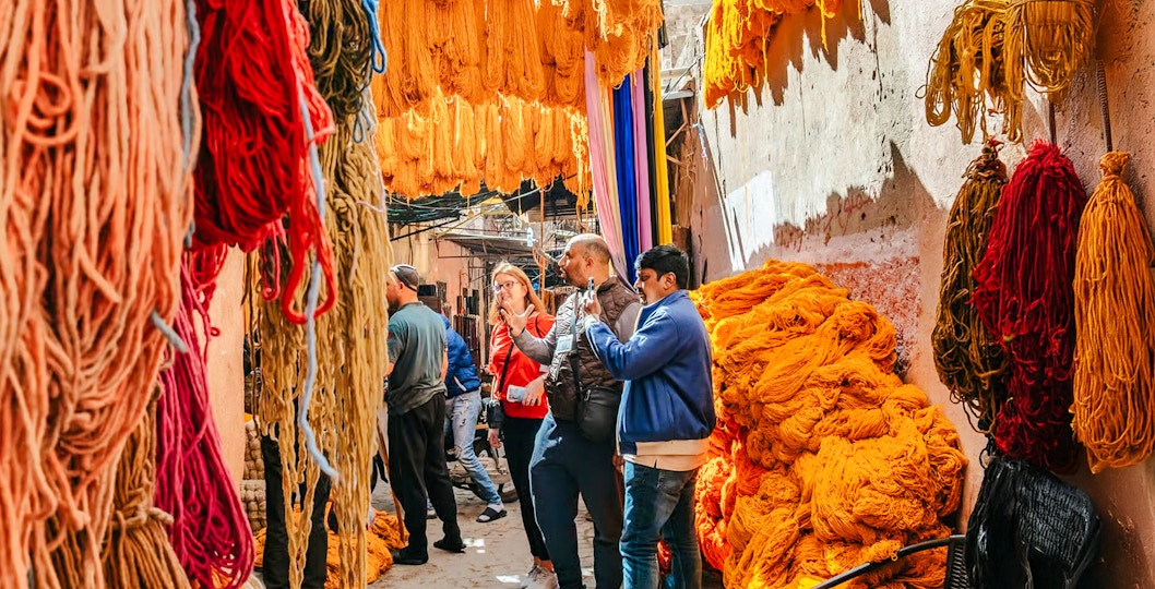 Visitors exploring vibrant yarn displays in Marrakech souks during a private shopping tour.