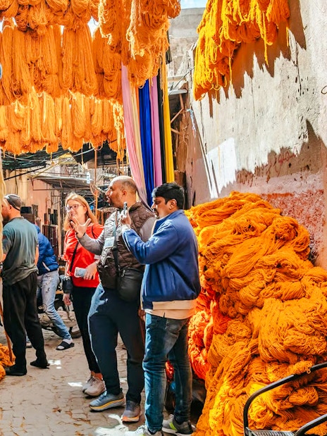 Visitors exploring vibrant yarn displays in Marrakech souks during a private shopping tour.