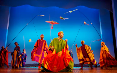 Performers in colorful costumes on stage during The Lion King musical.