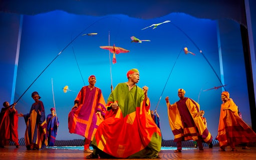 Performers in colorful costumes on stage during The Lion King musical.