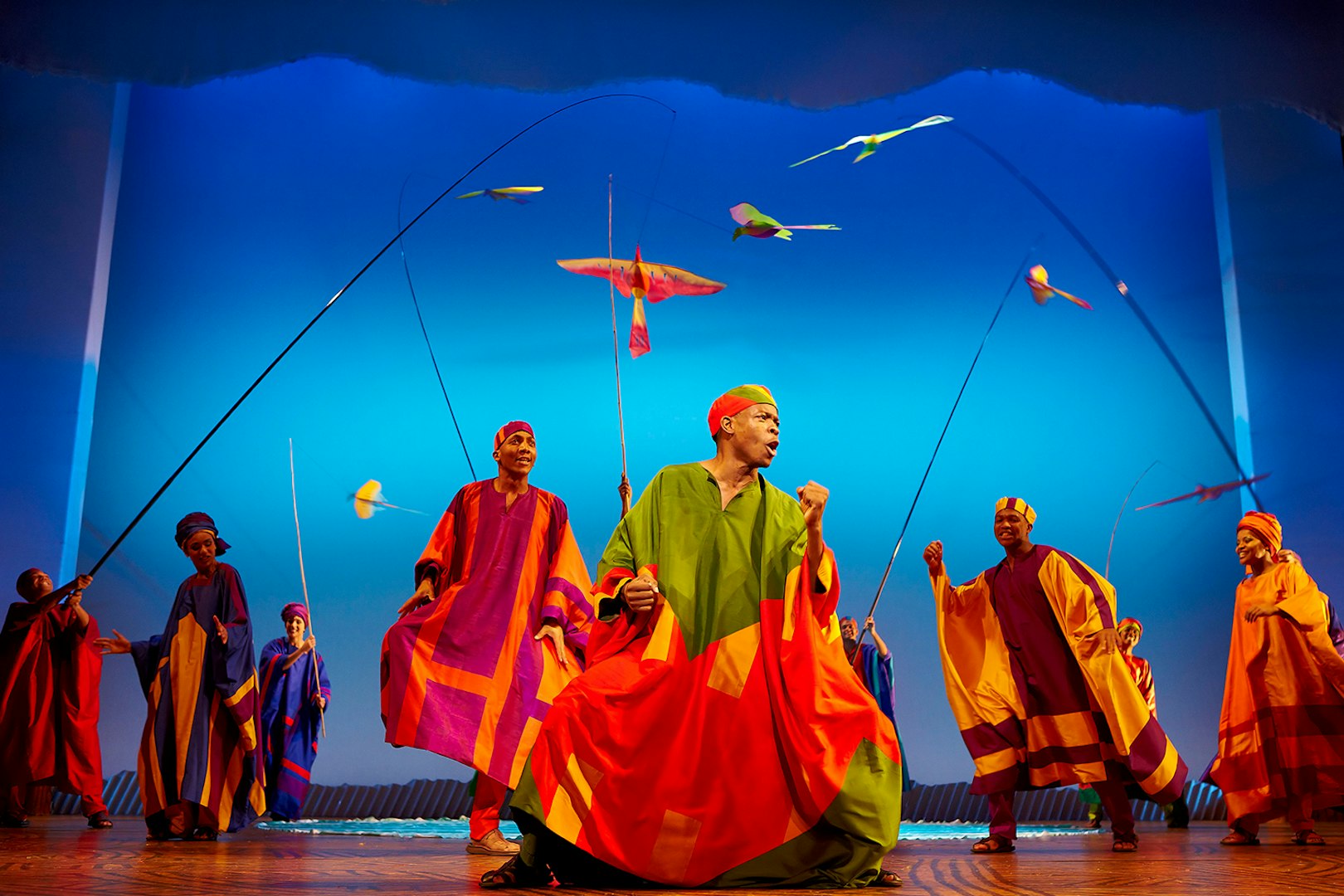 Performers in colorful costumes on stage during The Lion King musical.
