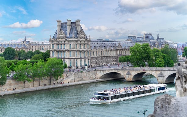 Seine River cruise boat passing by the Louvre Museum in Paris.