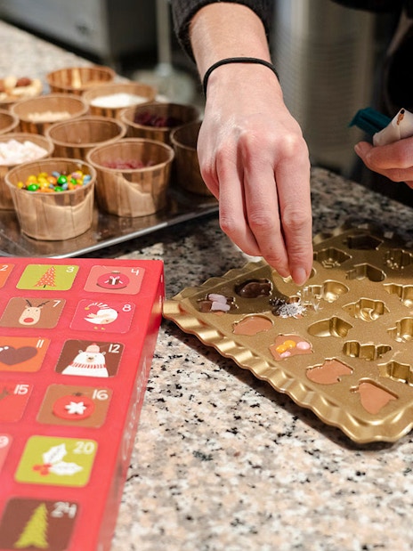 Creating chocolates at Choco-Story Brussels Museum with molds and toppings.