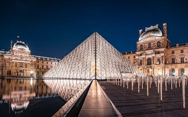 Louvre Pyramid illuminated at night in Paris, France.